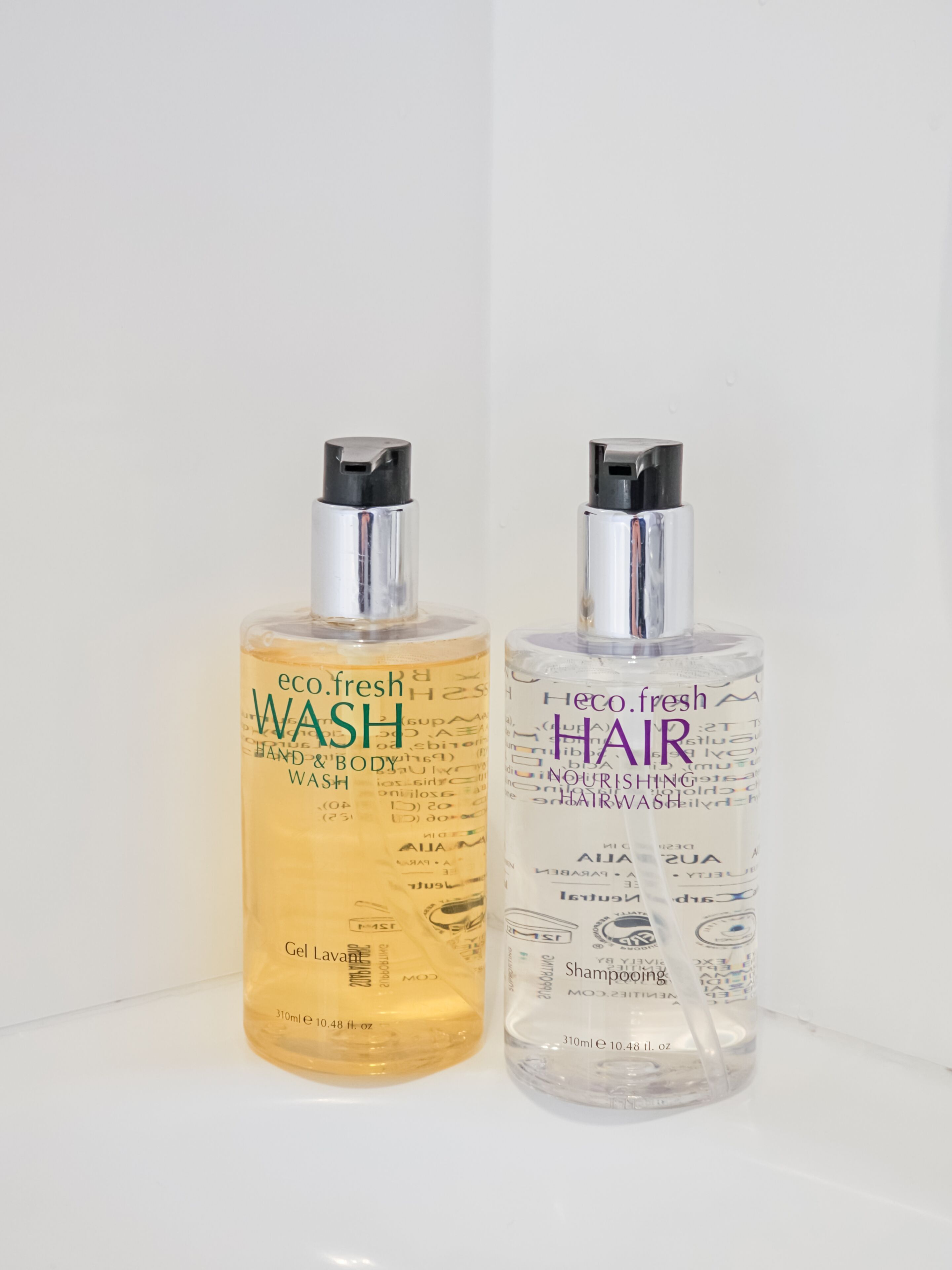 Two bottles of eco.fresh hair and body wash on a white surface.