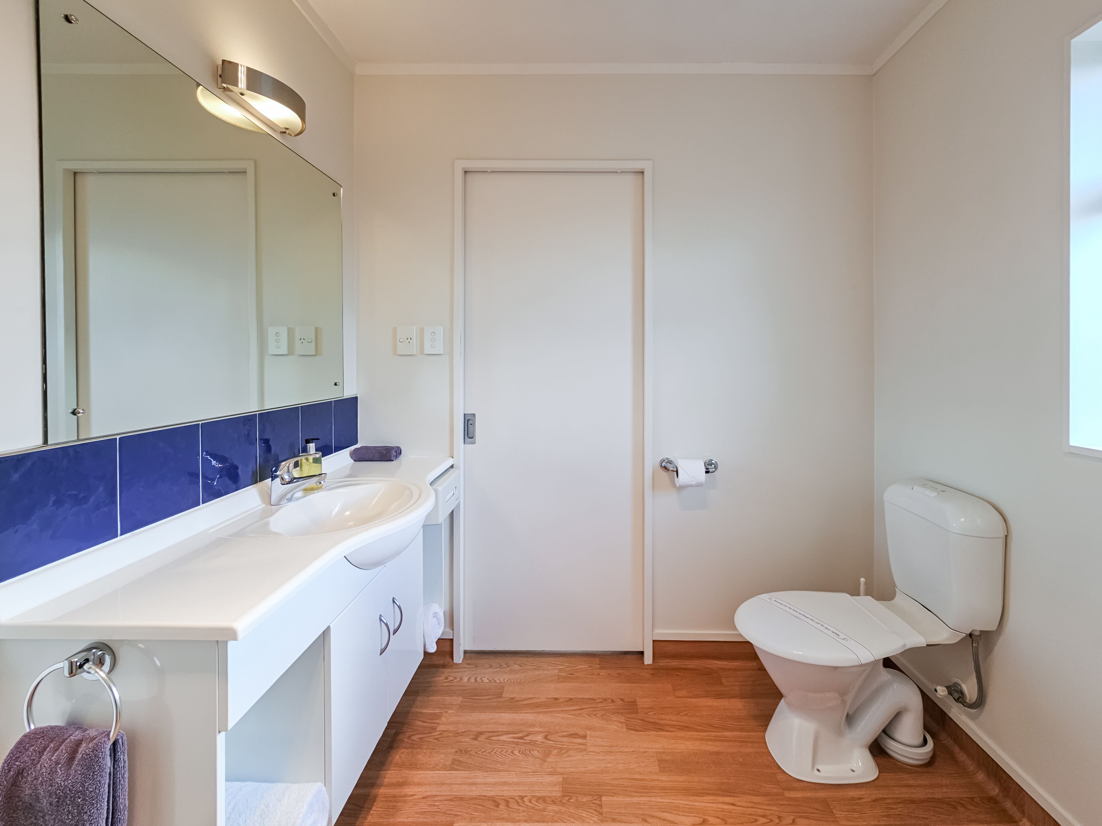 A bathroom with a white sink, mirror, and toilet.