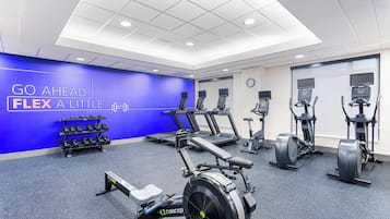 A gym with cardio machines, dumbbells, and a motivational wall.