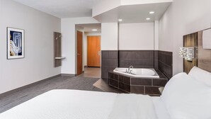 Ein modernes Hotelzimmer mit einem großen Bett, einem eigenen Badezimmer mit Badewanne und einem Korridor, der zu einem weiteren Zimmer führt.