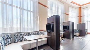 Ein modernes Hotelzimmer mit einer Couch, einem Flachbildfernseher, einem kleinen Tisch und einer integrierten TV-Konsole.