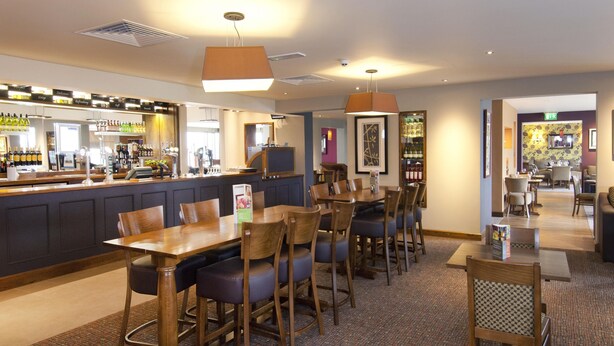 A hotel lobby with a bar area, seating arrangements, and a reception desk. - Premier Inn Heathrow Airport Terminal 5 (West Drayton)
