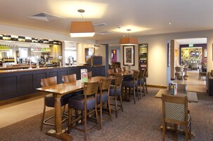 A hotel lobby with a bar area, seating arrangements, and a reception desk.