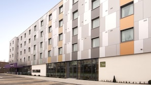 A modern building with a flat facade, multiple windows, and a sign indicating a pharmacy. - Premier Inn Heathrow Airport Terminal 5 (West Drayton)