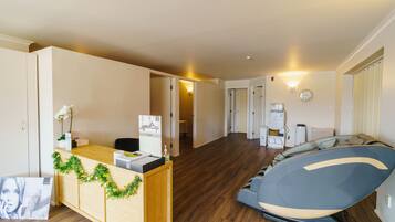A spacious living area with a wooden reception desk, a sofa, and a large flat-screen TV.