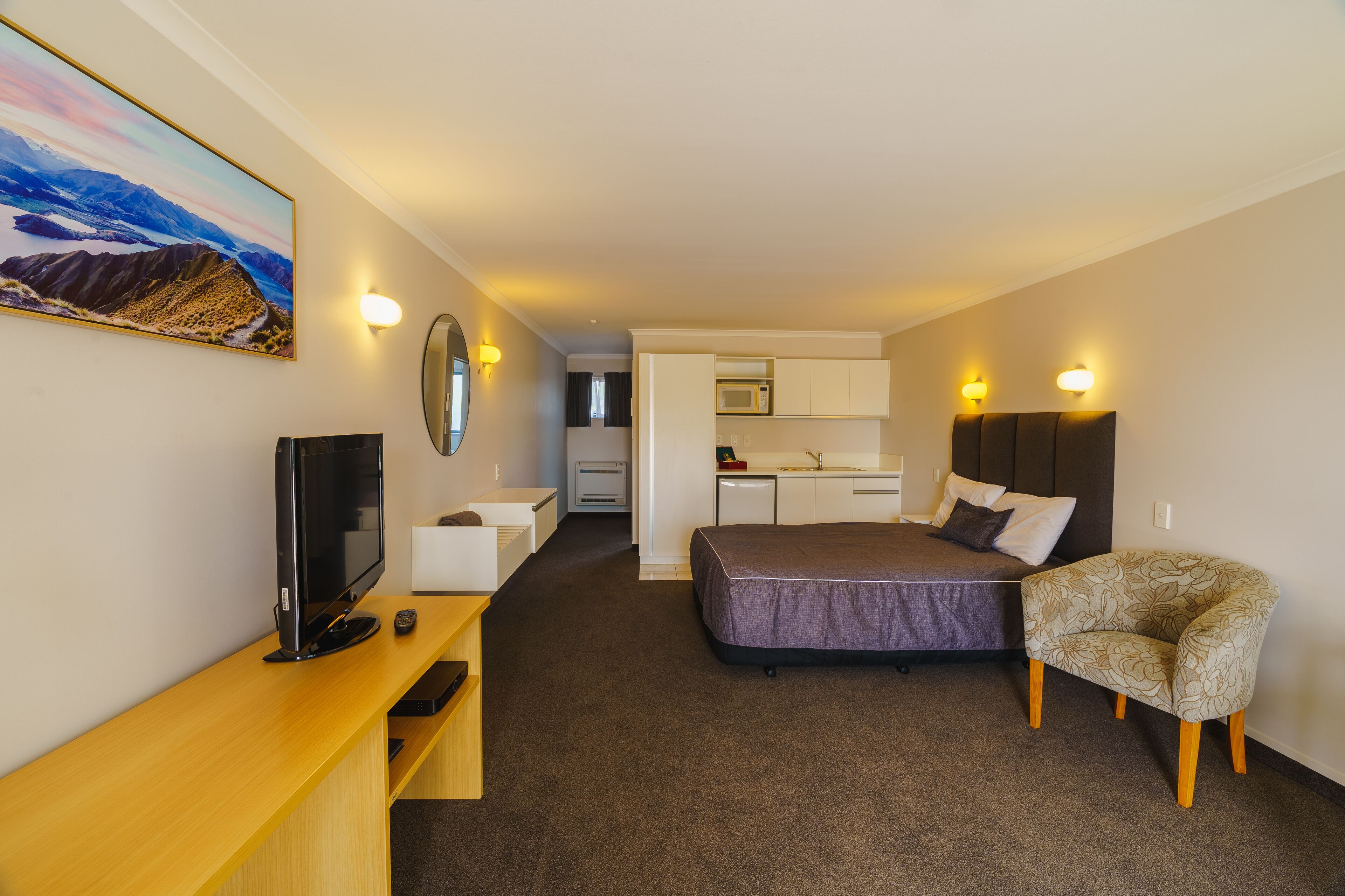 A hotel room with a bed, a TV, a desk, and a chair.