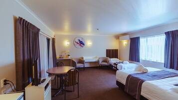 A hotel room with a bed, two armchairs, a desk, and a TV.