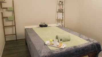 A neatly made bed with a green towel, a tray with toiletries, and a ladder against the wall.