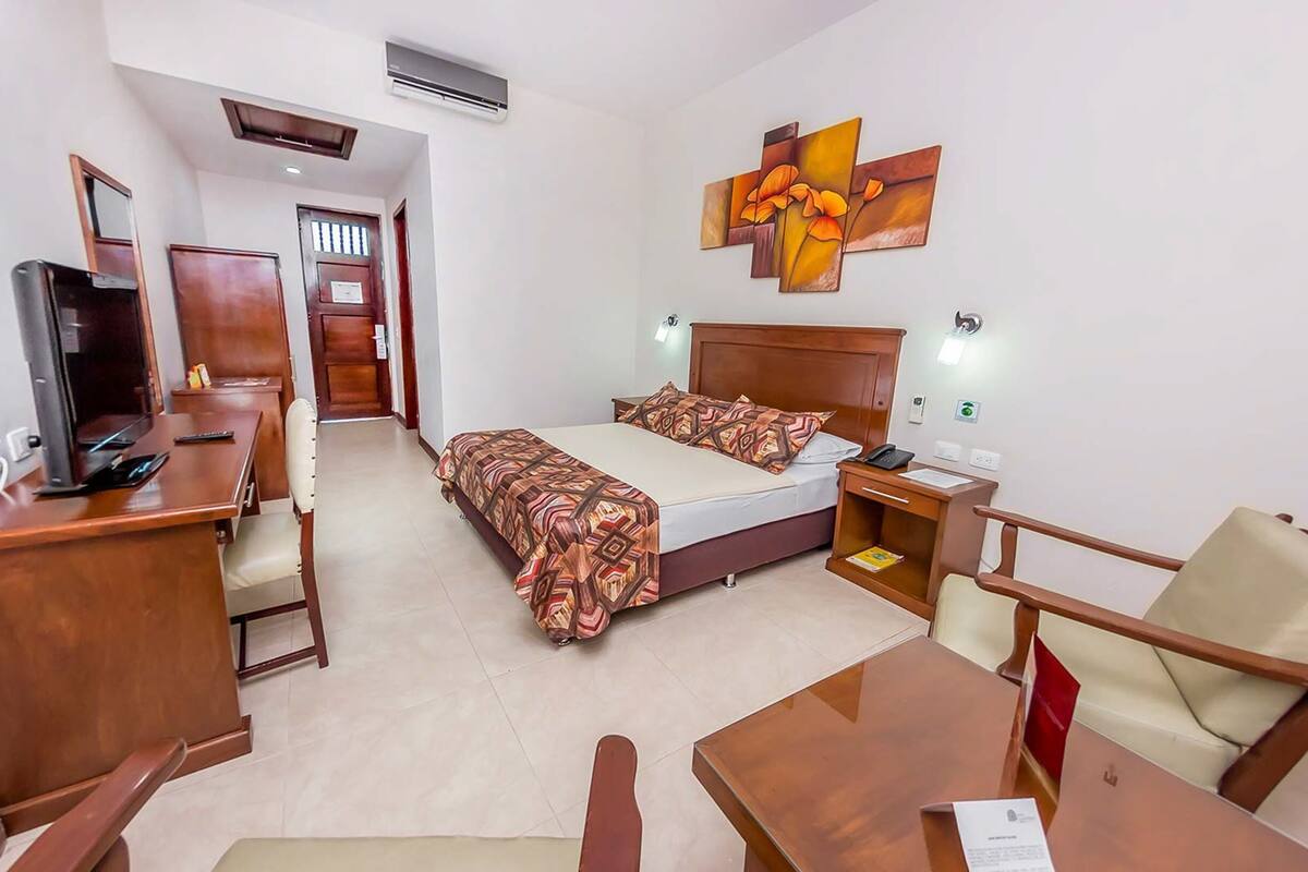 Habitación de hotel con cama, escritorio, silla y televisión.