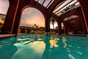 Una piscina con estructuras arqueadas, cielo despejado y un edificio al fondo.