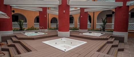 A rooftop spa area with multiple hot tubs and wooden deck seating.