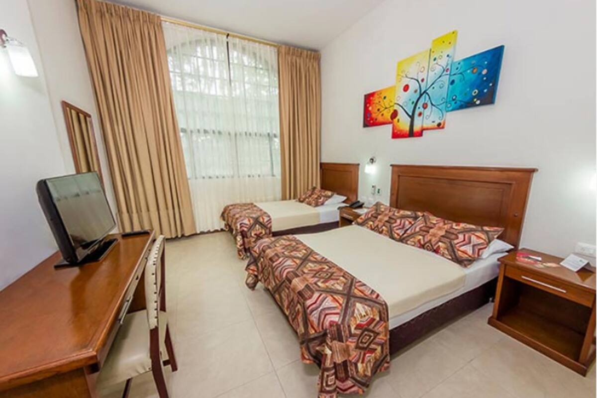 Una habitación de hotel con dos camas, un escritorio, un televisor y una mesita de noche.