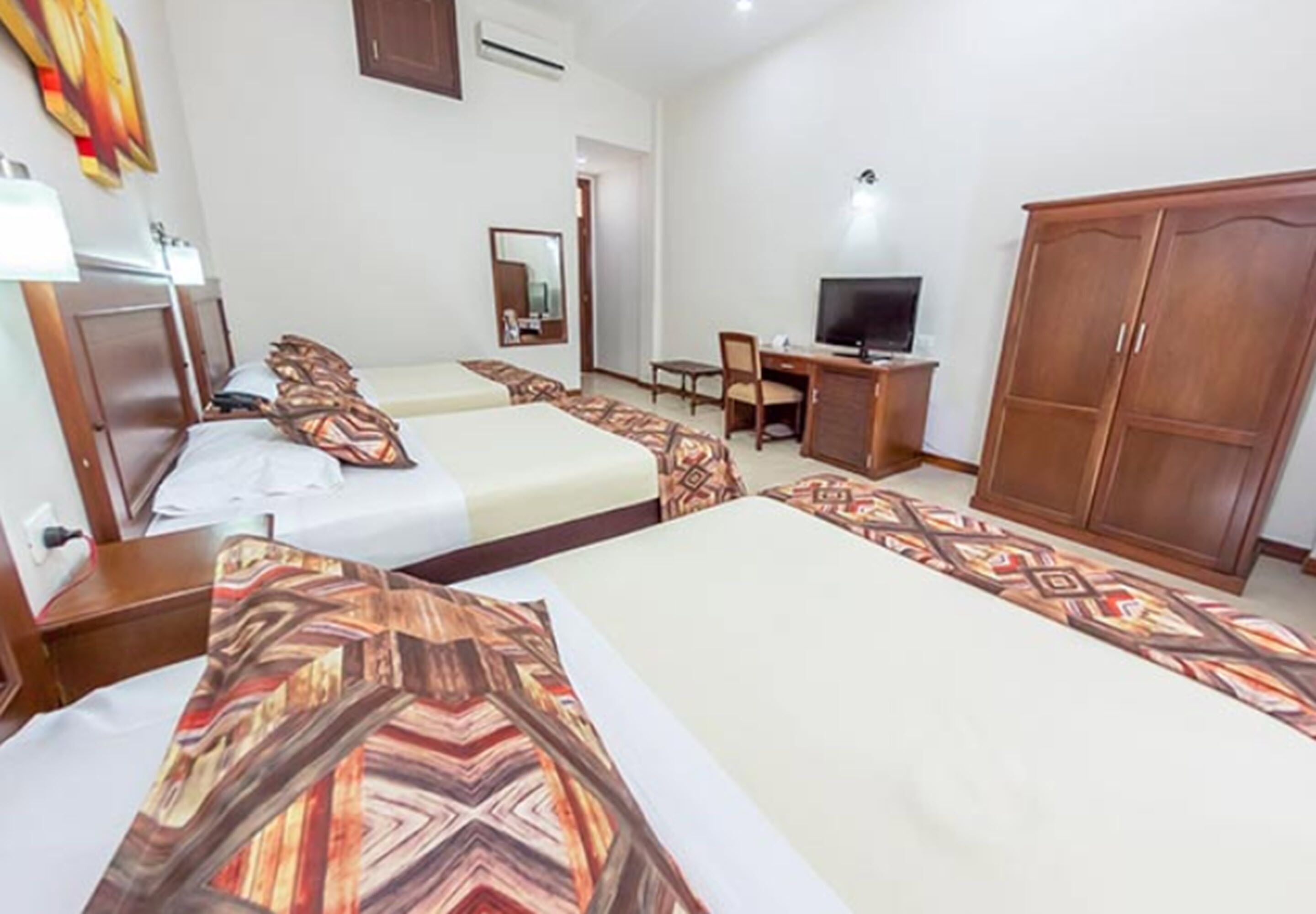 A hotel room with two beds, a desk, a television, and a wardrobe.