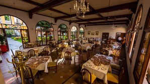 A restaurant with multiple tables and chairs, large windows, and a chandelier.