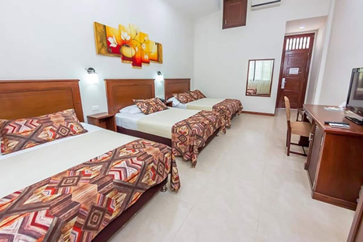 Habitación de hotel con tres camas, un escritorio y una silla.