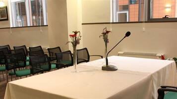 Ein Konferenzraum mit Reihen von Stühlen, einem Tisch mit einem Mikrofon und zwei Blumenvasen.