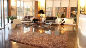 Una sala de estar moderna con un ventanal grande, un conjunto de sofás, una mesa de centro y una alfombra.