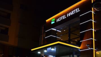 Un hotel llamado "HOTEL NARTEL" con un diseño moderno, que destaca un letrero llamativo y ventanas iluminadas.