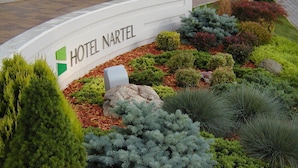 Un jardín ajardinado con un letrero del Hotel Nartel.