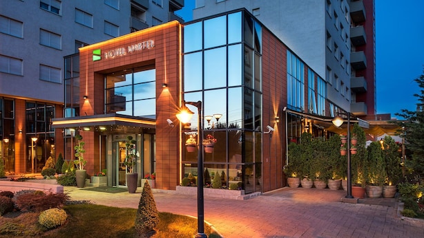 Un hotel moderno con fachada de vidrio, una entrada destacada e iluminación exterior.