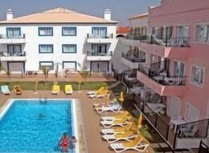 A hotel with a swimming pool, sun loungers, and a building with balconies. - Alagoa Azul Apartments (Castro Marim)