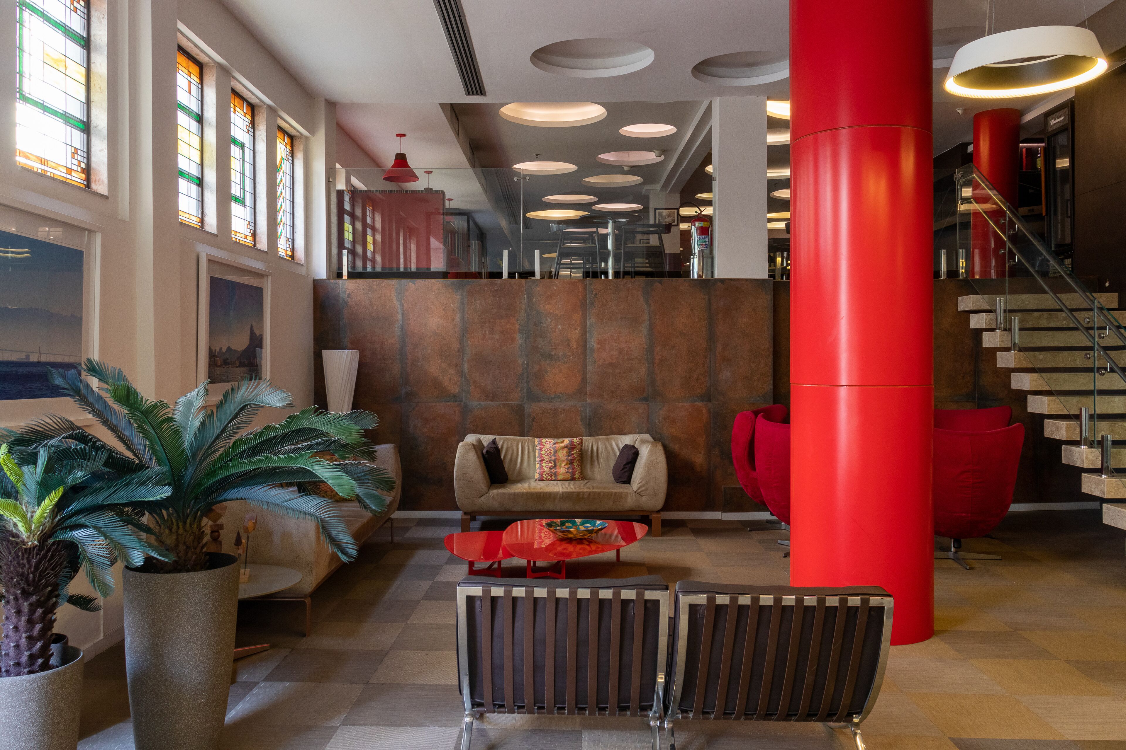 A lobby with a checkered floor, a sofa, a red pillar, and a staircase.