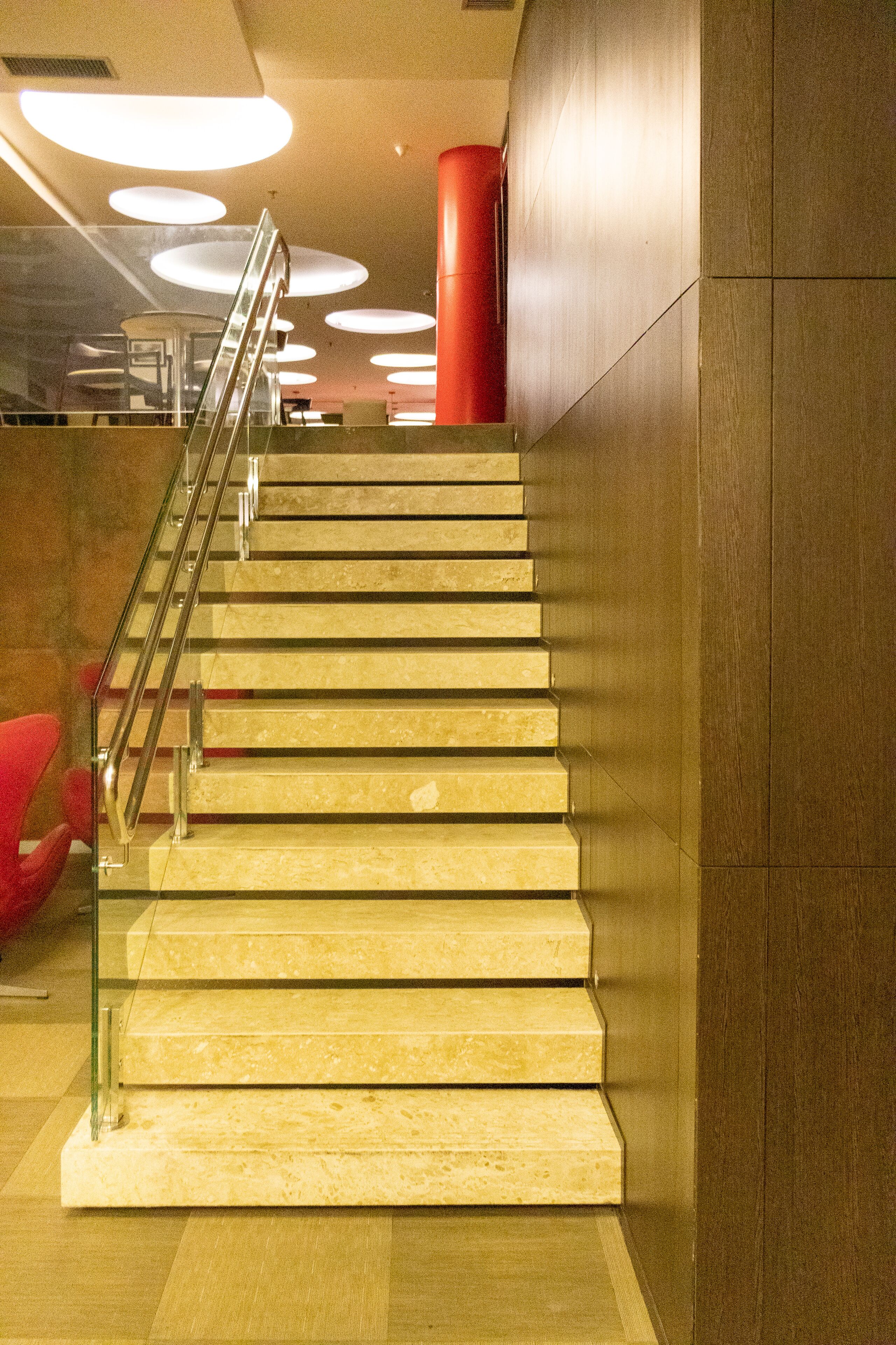 A staircase with glass railings and wooden steps, leading to an upper floor.