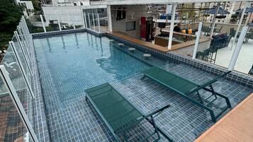 A rooftop pool with a bar area, seating, and a view of the cityscape.
