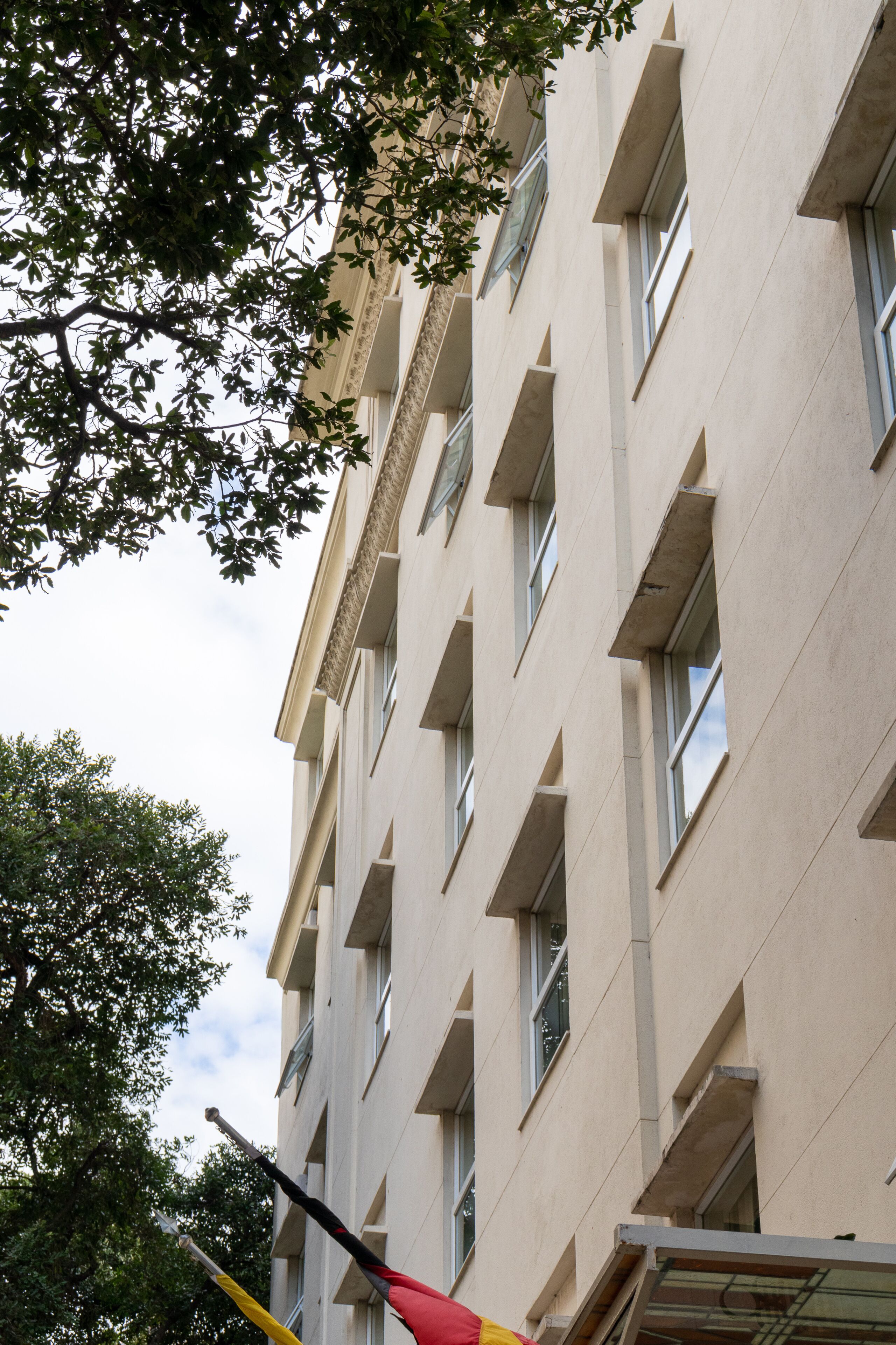 Un edificio de varios pisos con fachada simétrica, grandes ventanales y tejado plano.