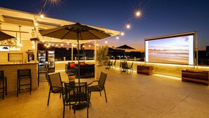 An outdoor patio area with a bar, seating, and a large screen for viewing. - Arosa Rio Hotel (Rio de Janeiro)