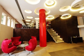 A modern lobby with a staircase, red chairs, and a large red pillar. - Arosa Rio Hotel (Rio de Janeiro)
