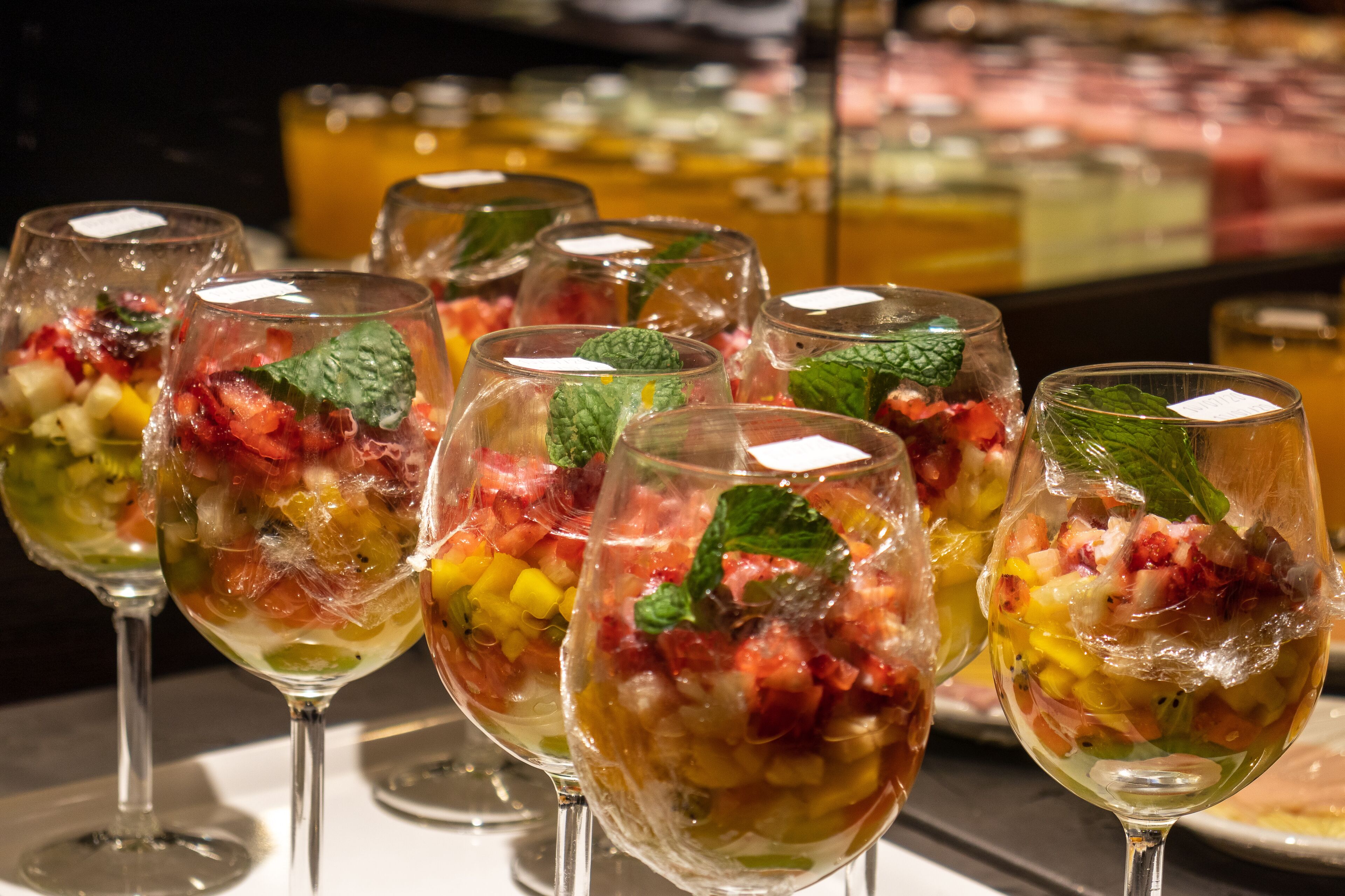 A selection of fruit-based beverages in clear glasses with mint leaves, displayed on a table.