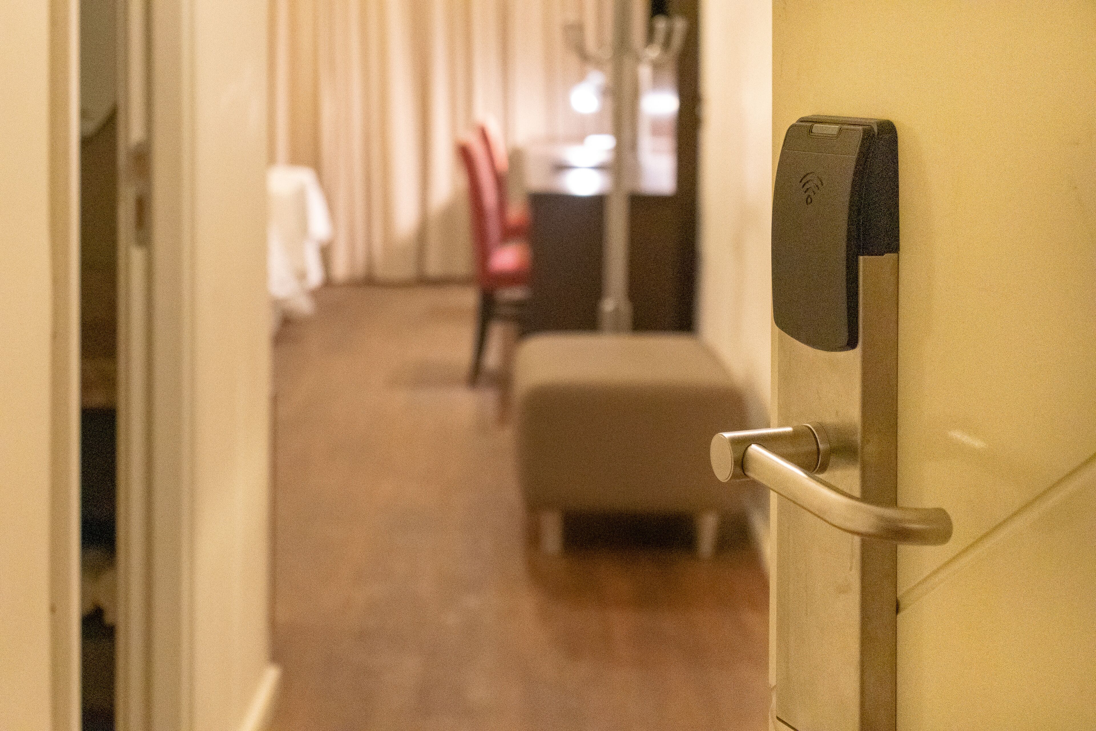 Un pasillo de hotel con una puerta, una silla y una pequeña mesa al fondo.