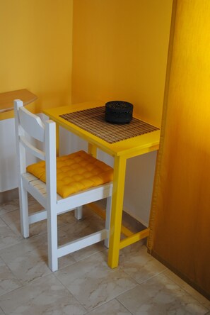 A small room with a white chair and a yellow table. - Karmik Concept Apartments (Rhodes)