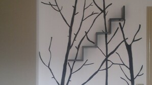 A wall with a black tree and staircase mural. - Karmik Concept Apartments (Rhodes)