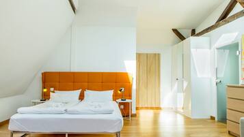 Un dormitorio moderno con una cama grande, vigas de madera, una mesita de noche pequeña y una mesita auxiliar.
