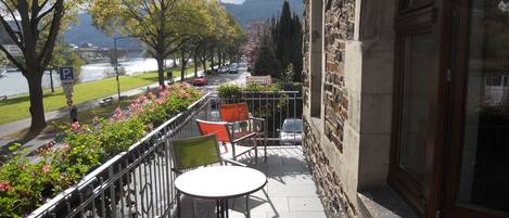 Un balcón con mobiliario exterior, vista de un río y un edificio de piedra.
