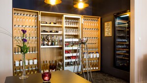 A bar area with shelves of wine bottles and glasses, a table with a candle, and a wine cooler. - Hotel Villa Vinum Cochem (Cochem)