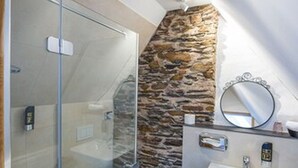 A modern bathroom with a glass shower enclosure, a stone accent wall, and a white sink with a mirror. - Hotel Villa Vinum Cochem (Cochem)
