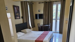 Ein Hotelzimmer mit Bett, Schreibtisch, Stuhl, Fernseher und Blick ins Freie.