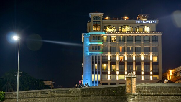 Un hotel con un letrero llamativo que dice "THE BAYLEAF" de noche, que presenta un estilo arquitectónico moderno con múltiples ventanas y balcones.