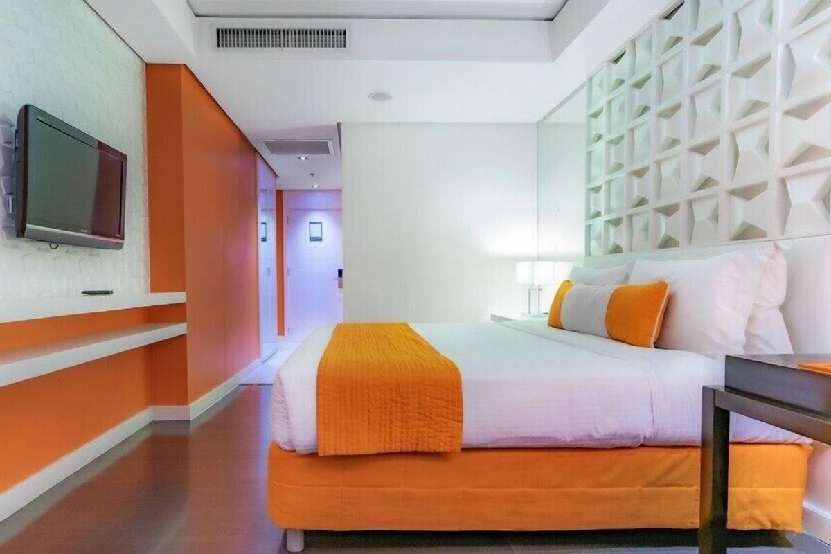 Ein Hotelzimmer mit Bett, Wandfernseher und einer weißen, strukturierten Trennwand.