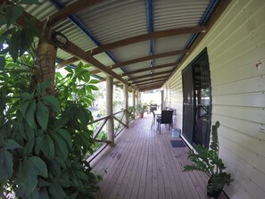 A covered porch with wooden flooring, potted plants, and a table with chairs. - Anchorage Weipa (Rocky Point)