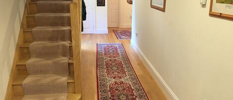 Una escalera con peldaños alfombrados que conduce a una puerta. Un tapete estampado está en el suelo.