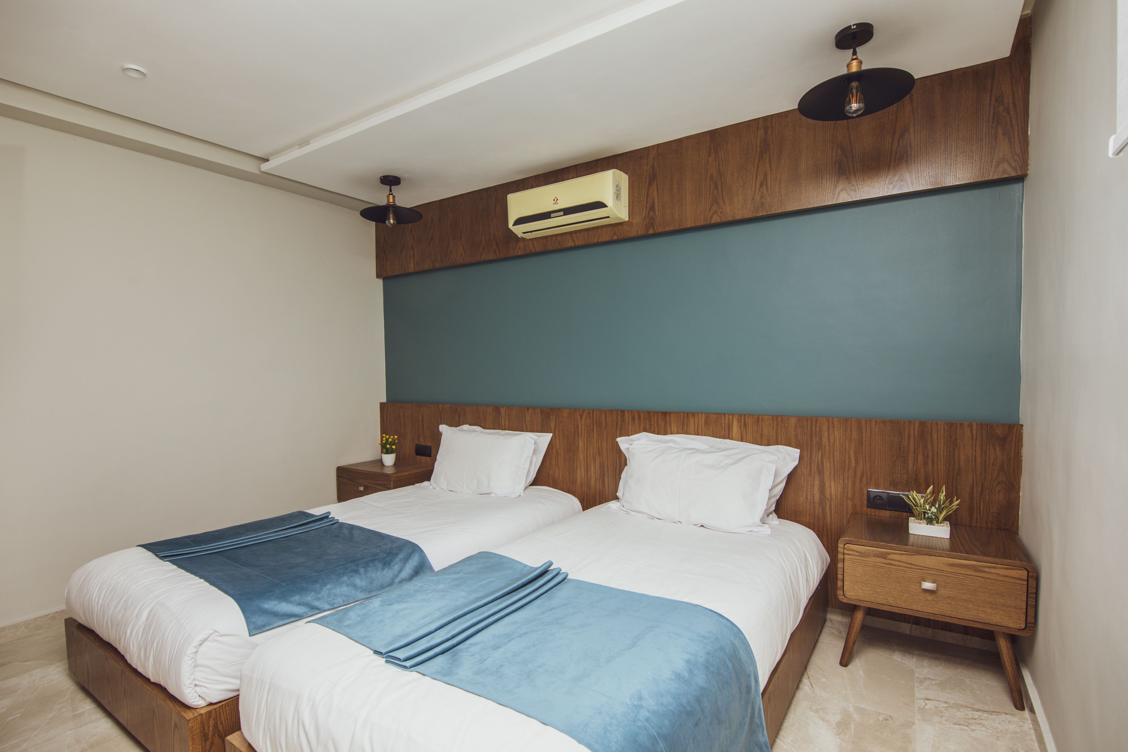 Une chambre d’hôtel moderne dotée d’un grand lit, d’une tête de lit en bois et d’un système de climatisation intégré.
