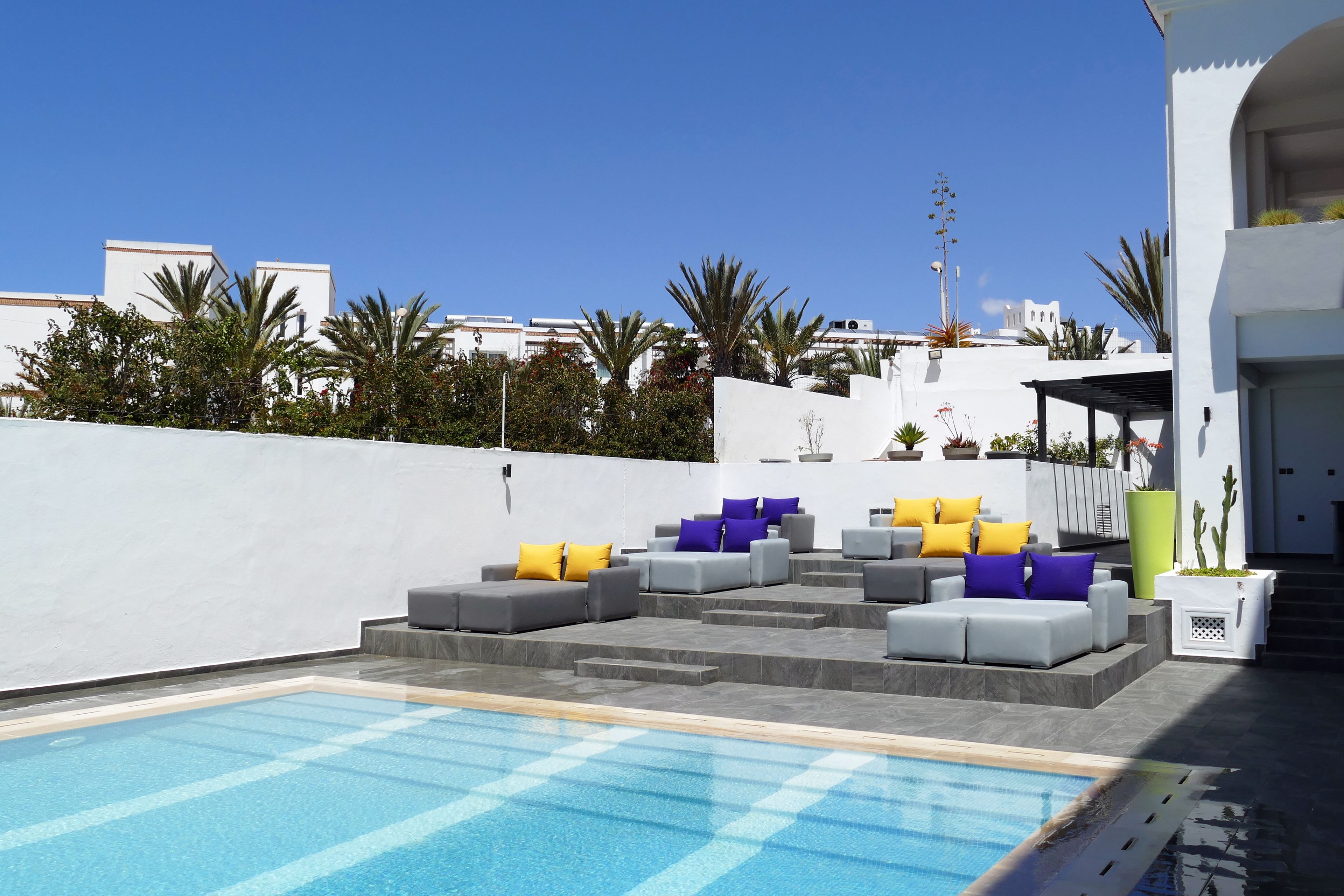Un área de piscina moderna al aire libre con asientos escalonados y cojines de colores.