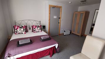 A bedroom with a bed, a chair, a wardrobe, and a heater.