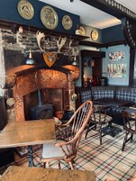Un interior rústico con chimenea de piedra, muebles de madera y platos decorativos en la pared.