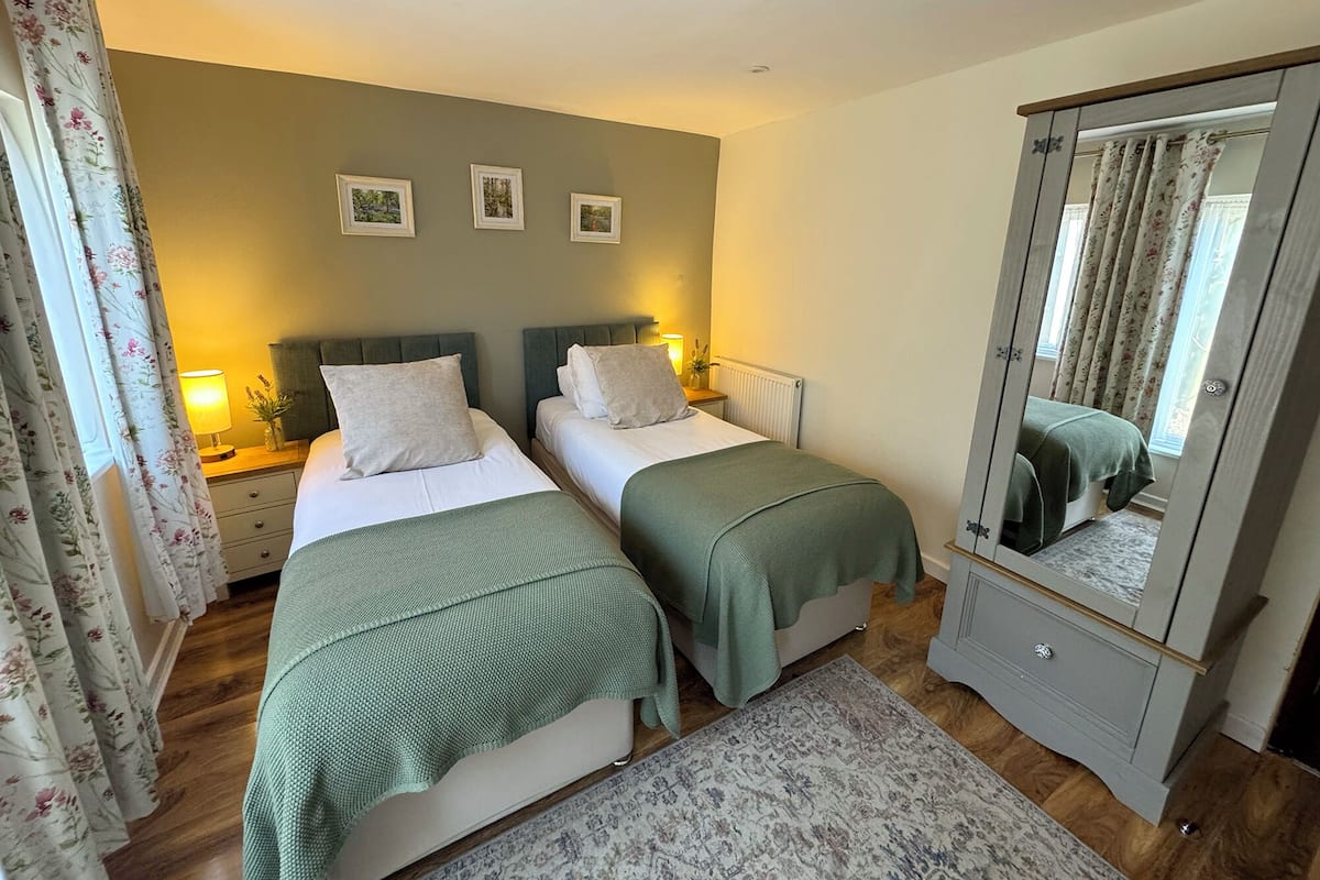 Quarto com duas camas, um espelho e uma cômoda.