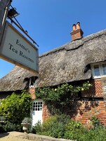 A traditional building with a thatched roof and a sign for Esme's Tea Rooms.